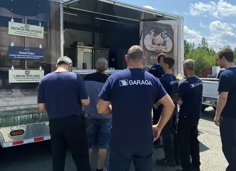 Des employés d’usine et de bureau Garaga St-Georges viennent chercher leur poutine gratuite. Une activité organisée pour célébrer l’arrivée du beau temps.